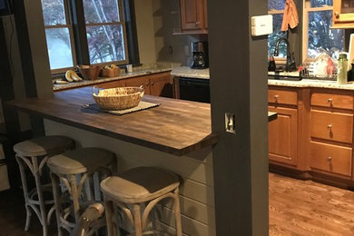Mid-sized arts and crafts u-shaped medium tone wood floor and brown floor kitchen photo in Atlanta with an undermount sink, raised-panel cabinets, medium tone wood cabinets, wood countertops, black appliances and a peninsula
