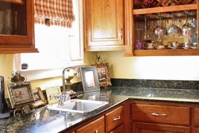 ニューオリンズにある小さなトラディショナルスタイルのおしゃれなキッチン (レイズドパネル扉のキャビネット、中間色木目調キャビネット、御影石カウンター) の写真