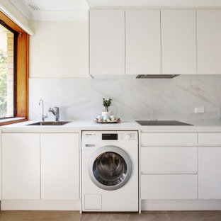 Photo of a contemporary l-shaped kitchen in Newcastle - Maitland with a drop-in sink, flat-panel cabinets, white cabinets, white splashback, no island, brown floor and white benchtop.