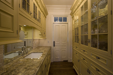 Enclosed kitchen - small traditional galley medium tone wood floor enclosed kitchen idea in Bridgeport with an undermount sink, beaded inset cabinets, yellow cabinets, granite countertops, beige backsplash, subway tile backsplash and paneled appliances