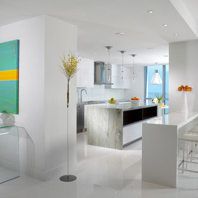 Example of a large trendy galley white floor and marble floor eat-in kitchen design in Miami with a double-bowl sink, white cabinets, marble countertops, white backsplash, glass sheet backsplash, stainless steel appliances, an island, gray countertops and flat-panel cabinets