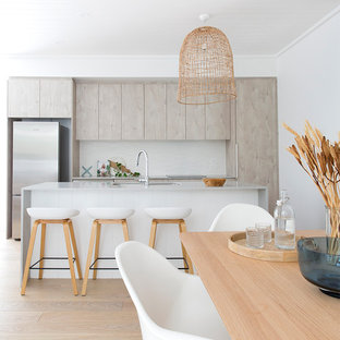 Photo of a beach style galley open plan kitchen in Brisbane with an undermount sink, flat-panel cabinets, grey cabinets, light hardwood floors, with island and beige floor.