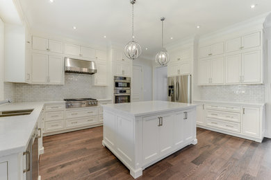 Large transitional u-shaped medium tone wood floor and brown floor eat-in kitchen photo in Toronto with an undermount sink, shaker cabinets, white cabinets, quartz countertops, white backsplash, stainless steel appliances, an island, gray countertops and subway tile backsplash