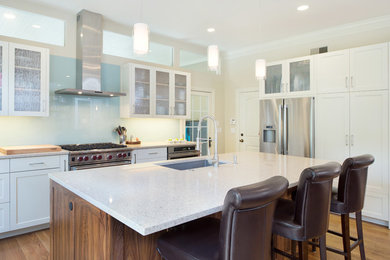 Inspiration for a mid-sized contemporary single-wall light wood floor open concept kitchen remodel in Kansas City with a single-bowl sink, shaker cabinets, white cabinets, quartz countertops, blue backsplash, glass sheet backsplash, stainless steel appliances and an island