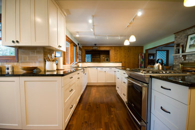 Example of a classic dark wood floor kitchen pantry design in Minneapolis with a farmhouse sink, recessed-panel cabinets, white cabinets, granite countertops, beige backsplash, ceramic backsplash, stainless steel appliances and an island