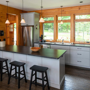 Esempio di una cucina a L stile rurale con ante grigie, top in quarzo composito, elettrodomestici in acciaio inossidabile, top nero, lavello a doppia vasca, ante lisce, paraspruzzi a finestra, parquet scuro, isola e pavimento marrone