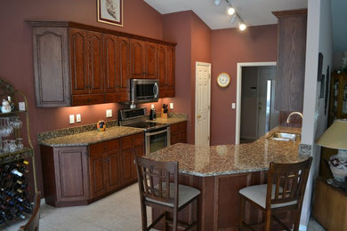 Example of a small classic u-shaped ceramic tile eat-in kitchen design in St Louis with a double-bowl sink, raised-panel cabinets, dark wood cabinets, granite countertops, stainless steel appliances and a peninsula