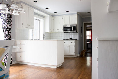Klassisk inredning av ett avskilt, mellanstort l-kök, med en nedsänkt diskho, luckor med infälld panel, vita skåp, bänkskiva i koppar, vitt stänkskydd, stänkskydd i keramik, rostfria vitvaror, mellanmörkt trägolv och en halv köksö