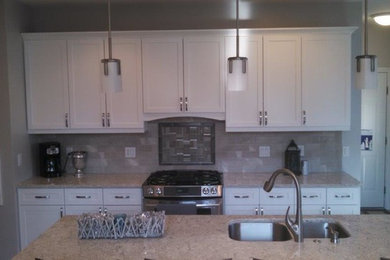 Cette photo montre une cuisine américaine tendance de taille moyenne avec un évier 2 bacs, des portes de placard blanches, un électroménager en acier inoxydable et îlot.