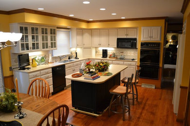 Example of a mid-sized classic l-shaped medium tone wood floor eat-in kitchen design in St Louis with a double-bowl sink, raised-panel cabinets, white cabinets, quartz countertops, white backsplash, ceramic backsplash, stainless steel appliances and an island