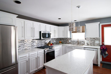 Foto på ett kök, med vita skåp och en köksö