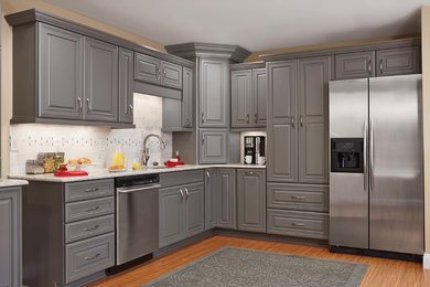 Example of a mid-sized trendy l-shaped medium tone wood floor and brown floor eat-in kitchen design in Orange County with an undermount sink, raised-panel cabinets, gray cabinets, quartz countertops, multicolored backsplash, subway tile backsplash, stainless steel appliances and no island