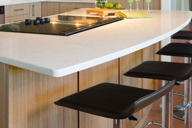 Idee per una cucina minimal con ante lisce, ante in legno chiaro, top in laminato, paraspruzzi bianco, elettrodomestici in acciaio inossidabile e pavimento in legno massello medio