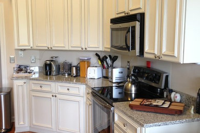 チャールストンにある中くらいなトラディショナルスタイルのおしゃれなL型キッチン (インセット扉のキャビネット、白いキャビネット、御影石カウンター、シルバーの調理設備、濃色無垢フローリング、茶色い床、グレーのキッチンカウンター) の写真