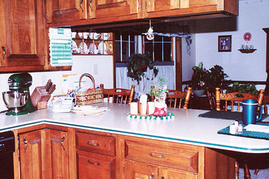 This is an example of a medium sized l-shaped kitchen pantry in Other with a double-bowl sink, glass-front cabinets, dark wood cabinets, granite worktops, black appliances, medium hardwood flooring and an island.