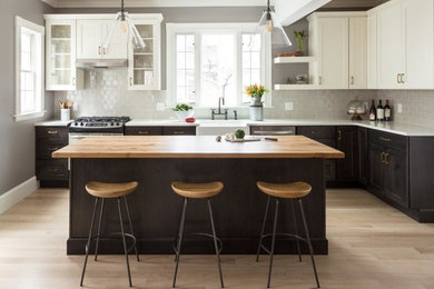 Immagine di un cucina con isola centrale classico con lavello stile country, elettrodomestici in acciaio inossidabile e pavimento in legno massello medio
