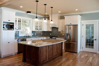 Eat-in kitchen - large traditional l-shaped medium tone wood floor eat-in kitchen idea in Other with an undermount sink, white cabinets, granite countertops, blue backsplash, subway tile backsplash, stainless steel appliances and an island