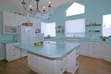 Example of a light wood floor kitchen design in San Francisco with white cabinets, white appliances and an island