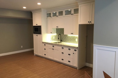Mid-sized transitional single-wall dark wood floor kitchen photo in Salt Lake City with a drop-in sink, shaker cabinets, white cabinets, granite countertops, gray backsplash, subway tile backsplash and stainless steel appliances