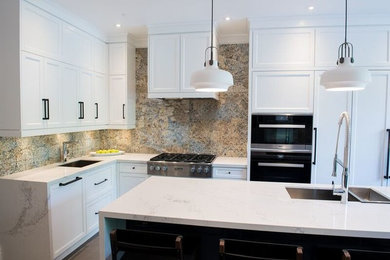 Mid-sized trendy l-shaped ceramic tile open concept kitchen photo in Toronto with a double-bowl sink, shaker cabinets, white cabinets, marble countertops, beige backsplash, stone slab backsplash, stainless steel appliances and an island