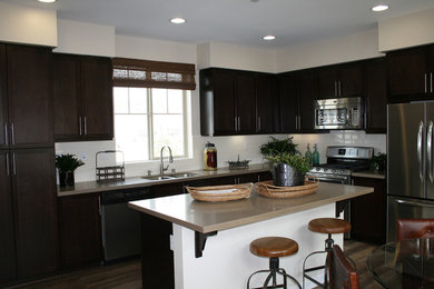 Example of a mid-sized transitional l-shaped dark wood floor and brown floor kitchen design in Oklahoma City with a double-bowl sink, shaker cabinets, dark wood cabinets, quartzite countertops, white backsplash, stainless steel appliances and an island