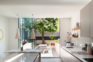 Einzeilige Moderne Küche mit flächenbündigen Schrankfronten, grauen Schränken und Kücheninsel in London