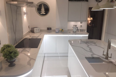 Large contemporary kitchen/diner in Other with quartz worktops, white splashback, an island and white worktops.