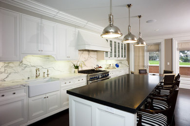 Example of a large minimalist l-shaped dark wood floor and brown floor eat-in kitchen design in San Francisco with a farmhouse sink, recessed-panel cabinets, white cabinets, marble countertops, white backsplash, stone slab backsplash, stainless steel appliances and an island