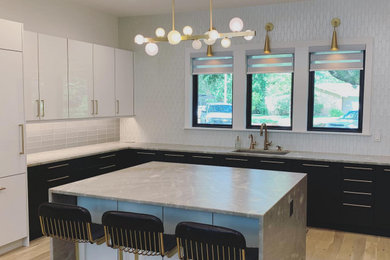 Moderne Küche in L-Form mit schwarzen Schränken, Marmor-Arbeitsplatte, Küchenrückwand in Weiß, hellem Holzboden, Kücheninsel, braunem Boden und grauer Arbeitsplatte in New Orleans