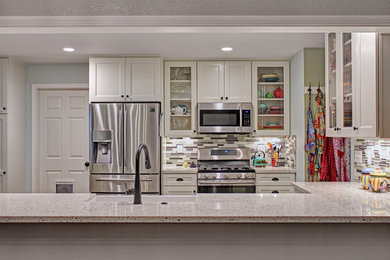 Mid-sized trendy u-shaped porcelain tile and gray floor open concept kitchen photo in Other with a farmhouse sink, recessed-panel cabinets, white cabinets, quartz countertops, multicolored backsplash, glass tile backsplash, stainless steel appliances, a peninsula and multicolored countertops