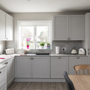 Photo of a medium sized classic l-shaped kitchen/diner in Other with a built-in sink, shaker cabinets, grey cabinets, grey splashback, black appliances, no island, grey floors and grey worktops.