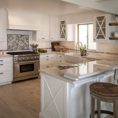 Kitchen - mid-sized coastal u-shaped kitchen idea in Los Angeles with a farmhouse sink, shaker cabinets, white cabinets, quartzite countertops, stainless steel appliances and a peninsula