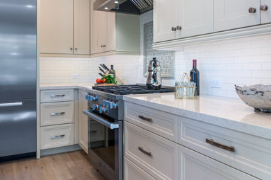 サンフランシスコにある中くらいなトラディショナルスタイルのおしゃれなキッチン (シェーカースタイル扉のキャビネット、白いキャビネット、白いキッチンパネル、シルバーの調理設備、シングルシンク、淡色無垢フローリング) の写真