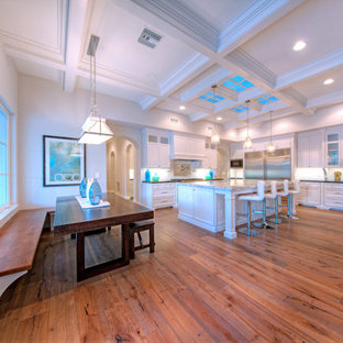 Large mediterranean eat-in kitchen designs - Eat-in kitchen - large mediterranean l-shaped medium tone wood floor eat-in kitchen idea in Phoenix with a farmhouse sink, recessed-panel cabinets, white cabinets, granite countertops, white backsplash, subway tile backsplash, stainless steel appliances and an island