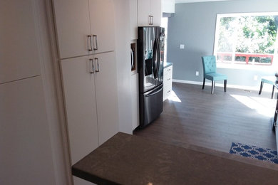 Example of a mid-sized trendy galley laminate floor and gray floor eat-in kitchen design in San Francisco with an undermount sink, flat-panel cabinets, white cabinets, quartzite countertops, blue backsplash, porcelain backsplash, black appliances and no island