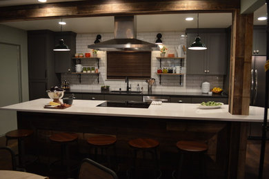Large rustic single-wall open plan kitchen in Sacramento with a submerged sink, shaker cabinets, grey cabinets, engineered stone countertops, white splashback, ceramic splashback, stainless steel appliances, dark hardwood flooring and an island.