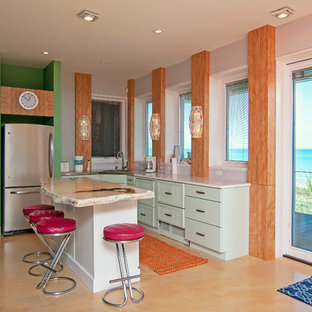 Photo of a beach style u-shaped kitchen in Chicago with an undermount sink, recessed-panel cabinets, green cabinets, green splashback, stainless steel appliances, with island, orange floor and white benchtop.