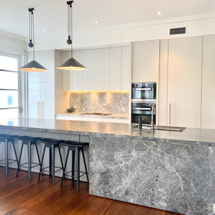 Inspiration for a large contemporary galley kitchen in Melbourne with grey cabinets, grey splashback, stone slab splashback, black appliances, dark hardwood floors, with island, brown floor, grey benchtop, an undermount sink and flat-panel cabinets.