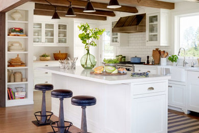 Mid-sized cottage single-wall medium tone wood floor eat-in kitchen photo in San Francisco with a farmhouse sink, shaker cabinets, white cabinets, marble countertops, white backsplash, subway tile backsplash, stainless steel appliances and an island