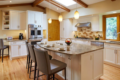 Inspiration for a large transitional l-shaped light wood floor eat-in kitchen remodel in Minneapolis with an undermount sink, white cabinets, quartz countertops, beige backsplash, glass tile backsplash, stainless steel appliances, an island and recessed-panel cabinets