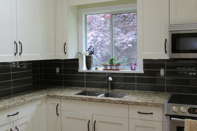 Example of a transitional kitchen design in Vancouver with a double-bowl sink, flat-panel cabinets, white cabinets, granite countertops, brown backsplash, glass sheet backsplash and stainless steel appliances