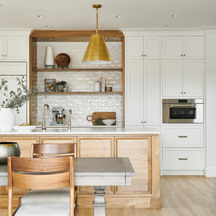 Design ideas for a large beach style l-shaped eat-in kitchen in Vancouver with a double-bowl sink, shaker cabinets, white cabinets, quartzite benchtops, white splashback, ceramic splashback, stainless steel appliances, vinyl floors, with island, beige floor and white benchtop.