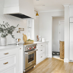 Large beach style l-shaped eat-in kitchen in Vancouver with a double-bowl sink, shaker cabinets, white cabinets, quartzite benchtops, white splashback, ceramic splashback, stainless steel appliances, vinyl floors, with island, beige floor and white benchtop.