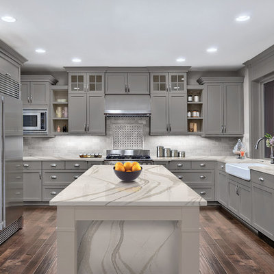 Inspiration for a transitional dark wood floor and brown floor kitchen remodel in Minneapolis with a farmhouse sink, shaker cabinets, gray cabinets, gray backsplash and an island