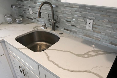 Small trendy l-shaped ceramic tile and gray floor eat-in kitchen photo in Tampa with an undermount sink, shaker cabinets, white cabinets, quartz countertops, multicolored backsplash, glass tile backsplash, no island and white countertops