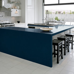 Inspiration for a large contemporary u-shaped eat-in kitchen in New York with flat-panel cabinets, white cabinets, quartz benchtops, white splashback, subway tile splashback, stainless steel appliances, ceramic floors, with island, a double-bowl sink, white floor and blue benchtop.