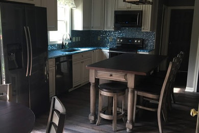 Inspiration for a mid-sized coastal l-shaped eat-in kitchen remodel in Other with a single-bowl sink, raised-panel cabinets, white cabinets, quartz countertops, blue backsplash, glass tile backsplash, stainless steel appliances and an island