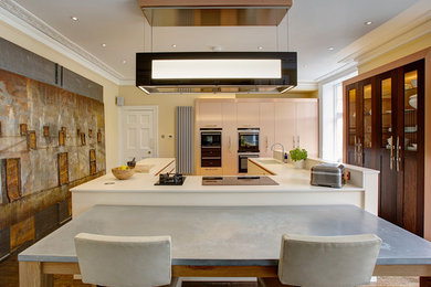 ケンブリッジシャーにある高級な広いコンテンポラリースタイルのおしゃれなキッチン (ドロップインシンク、フラットパネル扉のキャビネット、珪岩カウンター、ベージュキッチンパネル、パネルと同色の調理設備、磁器タイルの床) の写真