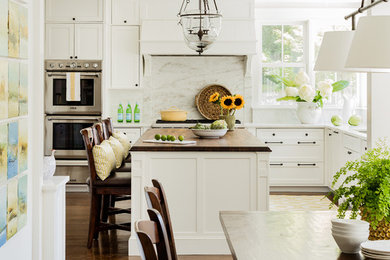 Kitchen - traditional dark wood floor and brown floor kitchen idea in Boston with an undermount sink, shaker cabinets, white cabinets, marble countertops, white backsplash, marble backsplash, paneled appliances and an island