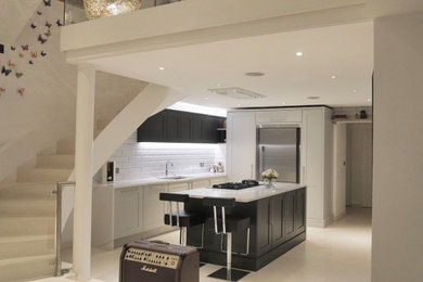 Design ideas for a large contemporary l-shaped kitchen/diner in London with an integrated sink, shaker cabinets, green cabinets, marble worktops, white splashback, marble splashback, stainless steel appliances, limestone flooring, an island, beige floors and white worktops.